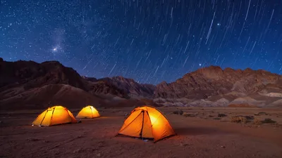 Three Illuminated Camping Tents Under Starry Night Sky