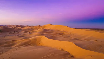 Vast Golden Sand Dunes Under A Purple Sunset Sky