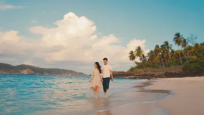 Young Couple Walking Along Tropical Beach Shoreline