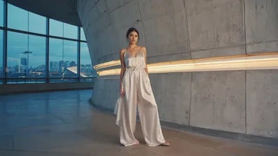 Elegant Woman In Silk Jumpsuit Standing In Modern Architecture