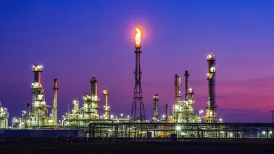 Oil Refinery Plant With Flare Stack At Sunset