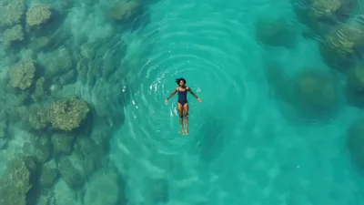 Woman Floating In Clear Tropical Ocean Water