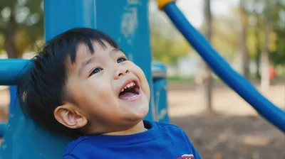Happy Toddler Boy Laughing On Playground Equipment