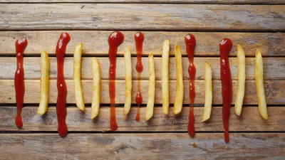 French Fries And Ketchup Lines On Wooden Table