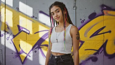 Young Woman With Braided Hair Standing Against Graffiti Wall