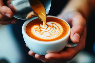 Barista Pouring Steamed Milk Into A Latte