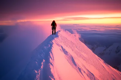 Mountaineer Standing On A Snowy Mountain Peak At Sunset