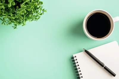 Top View Of Coffee Cup And Notebook On Green Desk