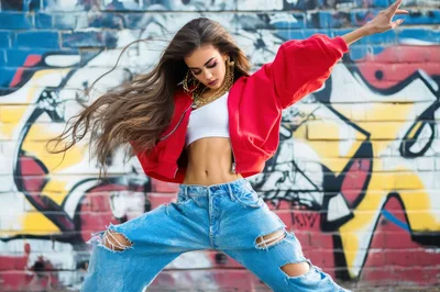 Young Woman Dancing In Streetwear Against Graffiti Wall