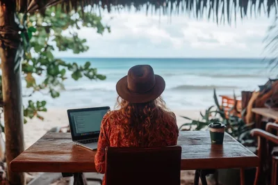 Woman Working On Laptop At Beachside Cafe