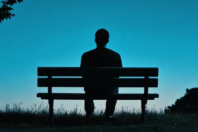 Silhouette Of A Man Sitting Alone On A Bench
