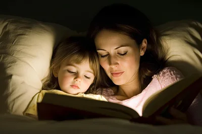 Mother Reading Bedtime Story To Young Daughter