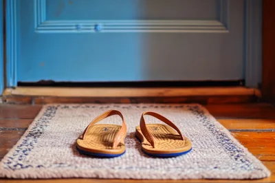 Pair Of Leather Flip Flops On A Doormat