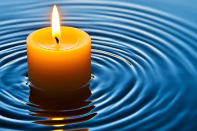 Yellow Candle Floating On Rippling Blue Water