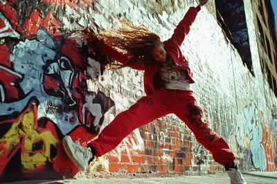 Young Woman Performing Street Dance Against Graffiti Wall