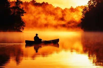 Silhouette Of A Person Paddling A Canoe At Sunrise