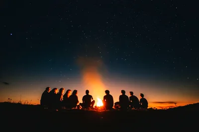 Group Of Friends Sitting Around A Campfire At Night