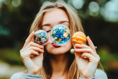 Young Woman Holding Miniature Planet Orbs