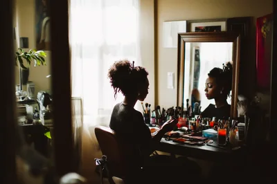 Young Woman Applying Makeup At A Vanity Mirror