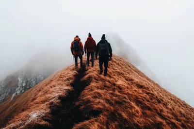 Three Hikers Trekking Along A Misty Mountain Ridge
