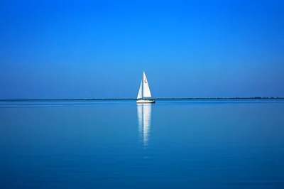 White Sailboat Sailing On Calm Blue Water