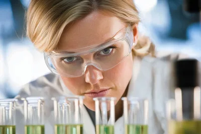 Female Scientist Examining Test Tubes In Laboratory