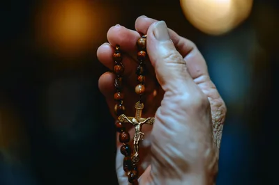 Elderly Person Holding A Wooden Rosary With Gold Crucifix
