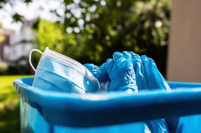 Used Medical Face Mask And Gloves In Blue Bin