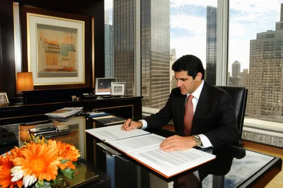 Businessman Signing Legal Documents In High Rise Office