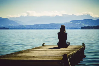 Woman Sitting In Meditation On A Wooden Pier
