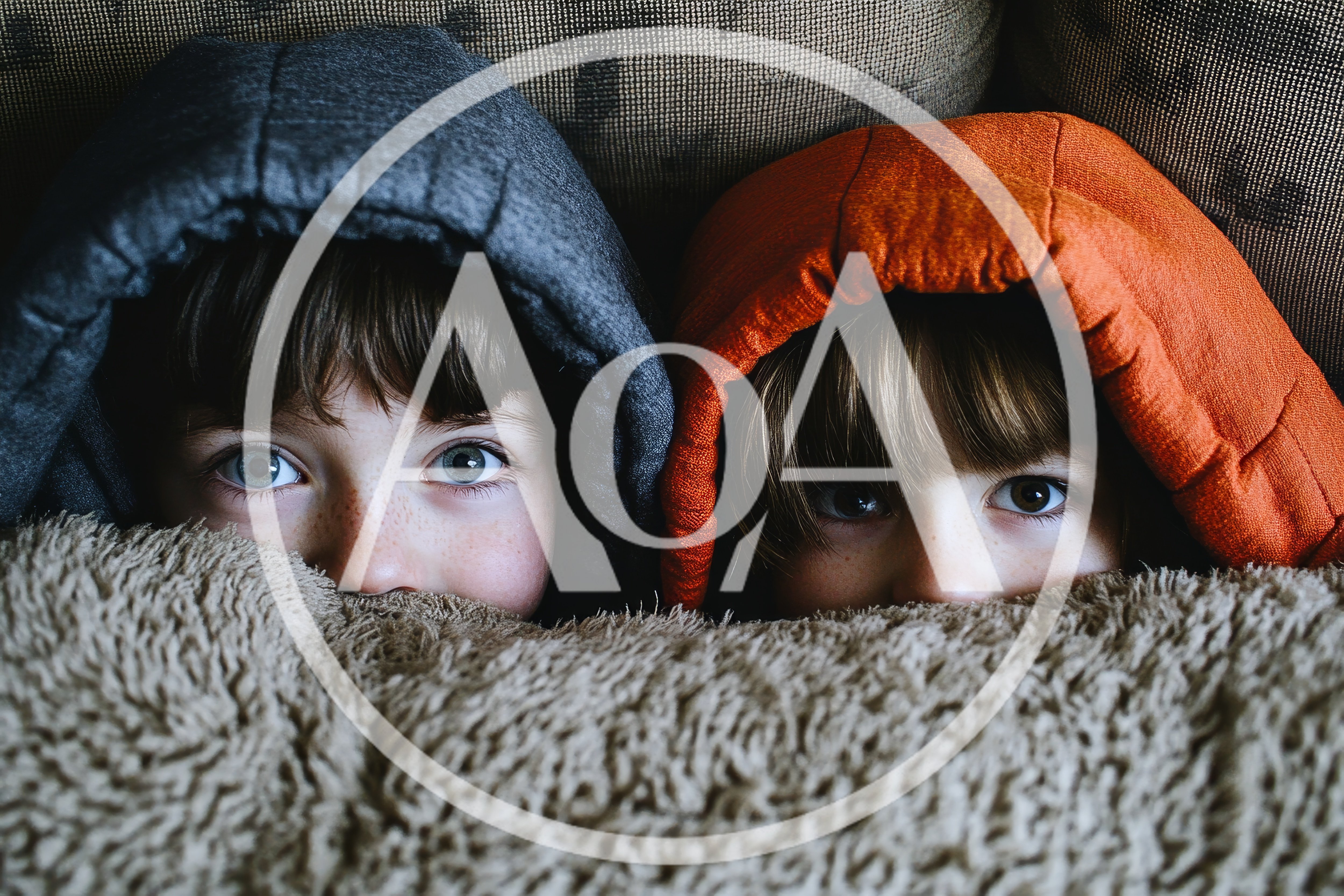 Two Children Peeking Out From Under A Blanket