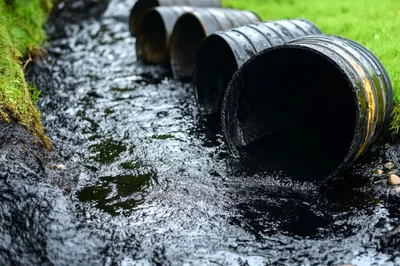 Oil Spilled From Barrels Into A Polluted Stream