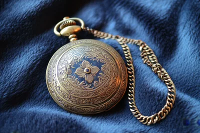 Antique Gold Pocket Watch Resting On Blue Velvet