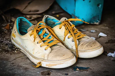 Pair Of Worn Out Yellow Sneakers On Concrete
