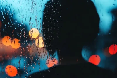 Silhouette Of A Person Looking Through A Rainy Window