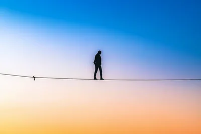Silhouette Of A Tightrope Walker Against A Sunset Sky