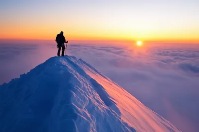 Mountaineer Standing On Snowy Mountain Peak At Sunrise
