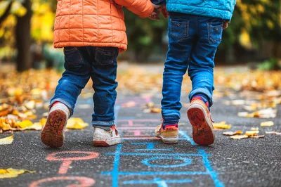 Two Children Playing Hopscotch on Autumn Path