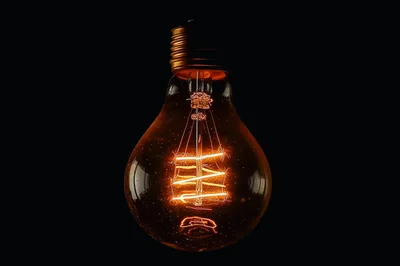 Glowing Vintage Edison Light Bulb Against Black Background