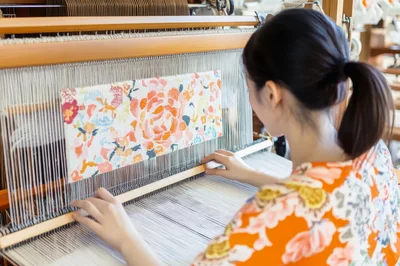Young Woman Weaving Floral Fabric on Traditional Loom