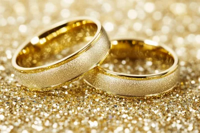 Two Gold Wedding Rings on Sparkling Glitter Background