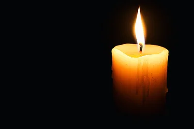 Single Lit Candle Burning In The Dark