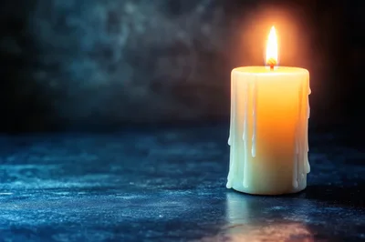 Lit Pillar Candle On Dark Textured Surface