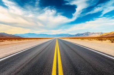 Empty Desert Highway Stretching Toward Distant Mountains