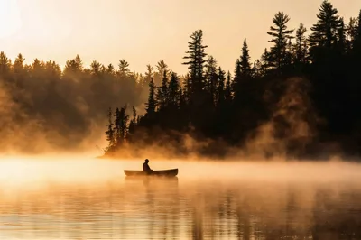 Lone Canoeist Paddling Through Morning Mist on Lake