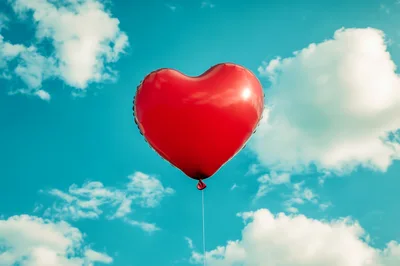 Red Heart Shaped Balloon Floating In Blue Sky