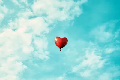 Red Heart Shaped Balloon Floating In Blue Sky