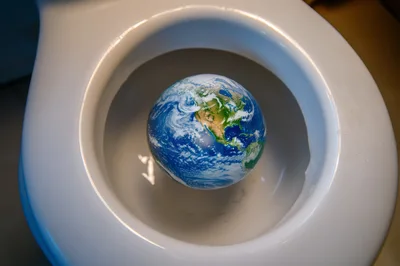 Planet Earth Floating Inside A White Toilet Bowl