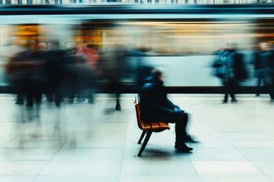 Commuter Sitting on Bench at Busy Train Station
