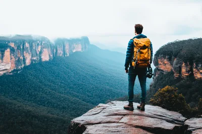 Hiker Standing On A Cliff Edge Overlooking A Valley